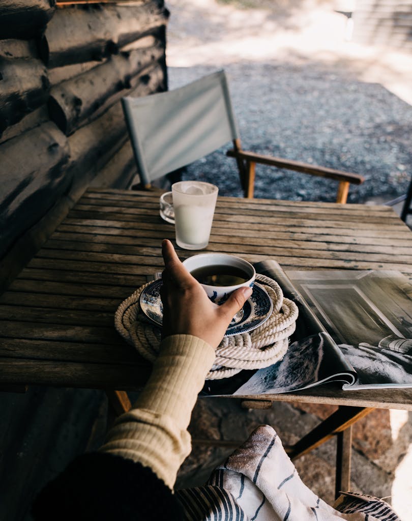 A cozy moment with tea on a rustic outdoor table by a cabin, capturing tranquility and comfort.